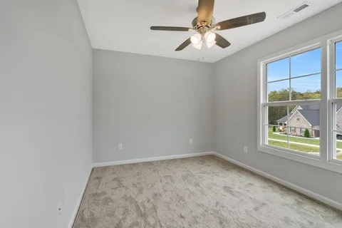 an empty room with windows and fan