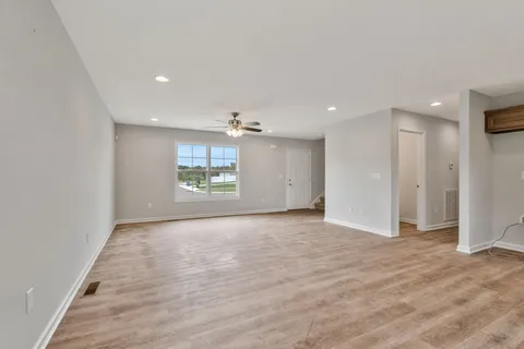 an empty room with wooden floor cabinet and windows