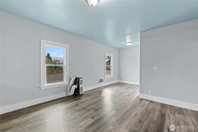 a view of an empty room with window and wooden floor