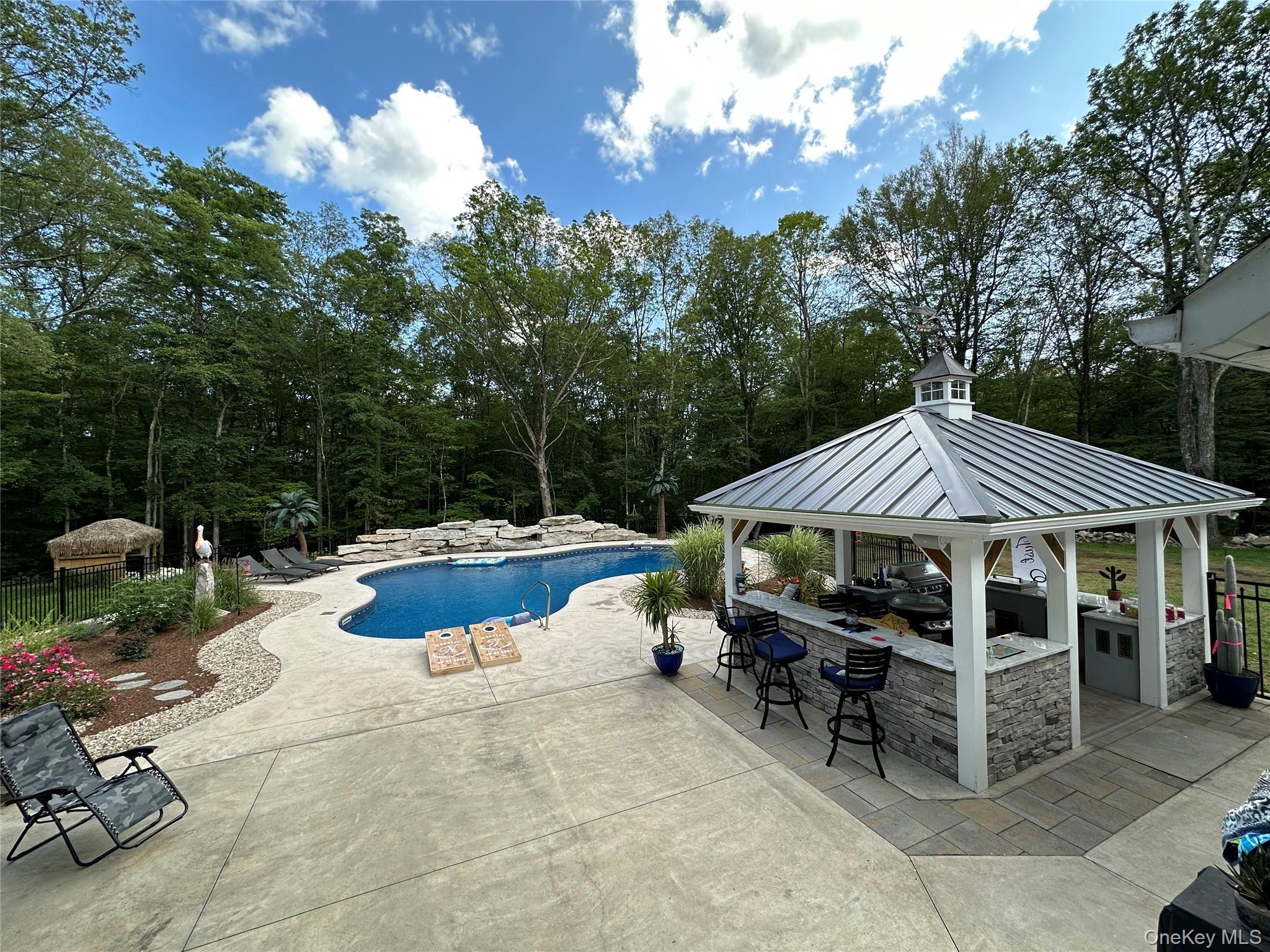 95 Weed Road Pine Bush, NY 12566 - Photo 23 of 31 Expansive outdoor living area featuring a freeform swimming pool with rock features, a stamped concrete patio, and mature trees