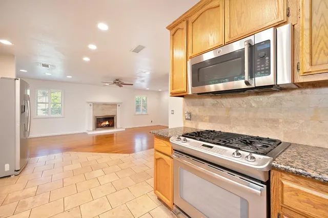 a kitchen with granite countertop a stove top oven microwave and cabinets