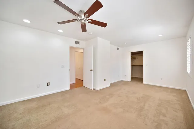 an empty room with ceiling fan and windows