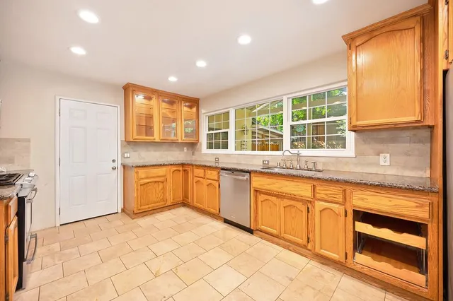 a kitchen with granite countertop a stove a sink and a refrigerator