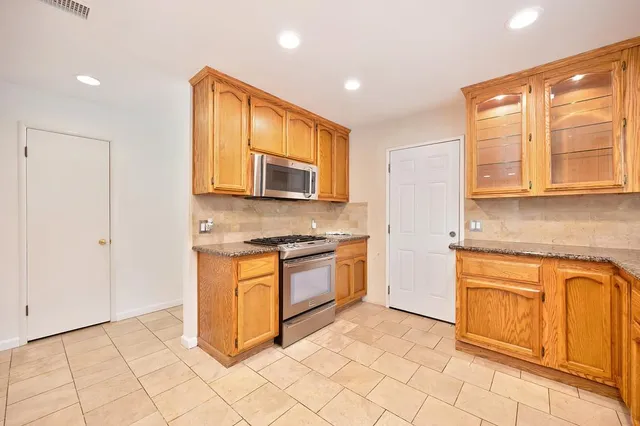 a kitchen with stainless steel appliances granite countertop a stove top oven microwave and cabinets