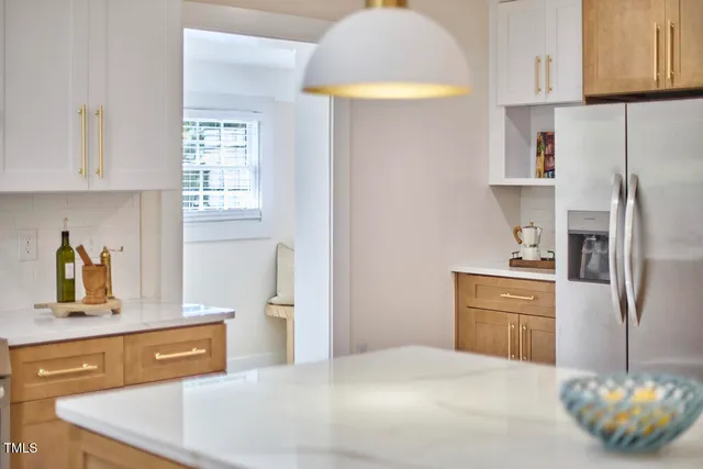 a kitchen with stainless steel appliances granite countertop a refrigerator a sink dishwasher a stove and white countertops with wooden floor