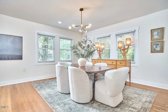 a dining room with chandelier and wooden floor