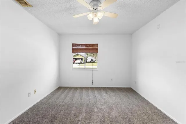 an empty room with a chandelier fan and windows