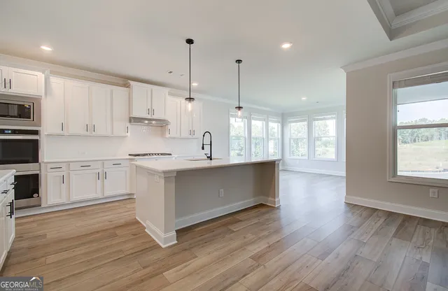 a kitchen with kitchen island white cabinets and stainless steel appliances