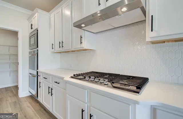 a kitchen with a sink a stove cabinets and wooden floor