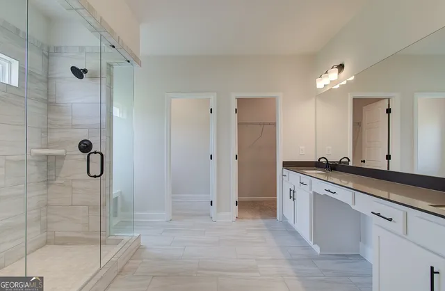 a large bathroom with a glass shower door and a sink
