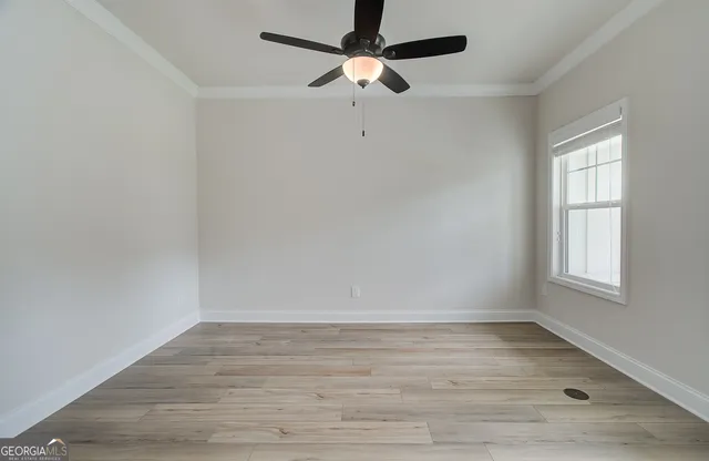 an empty room with wooden floor fan and windows