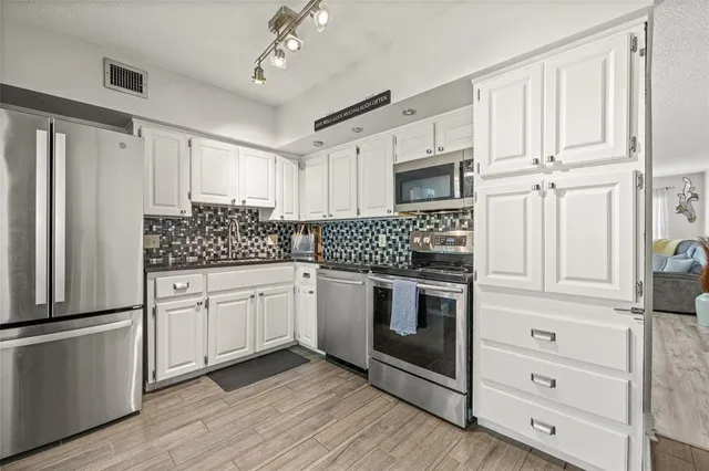a kitchen with stainless steel appliances white cabinets and a refrigerator