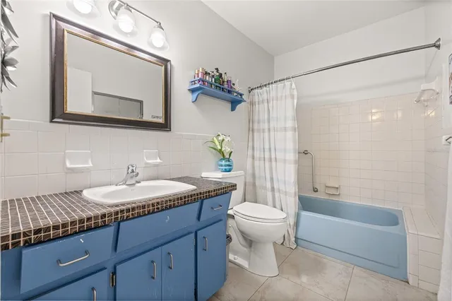 a bathroom with a granite countertop sink a toilet a mirror and shower