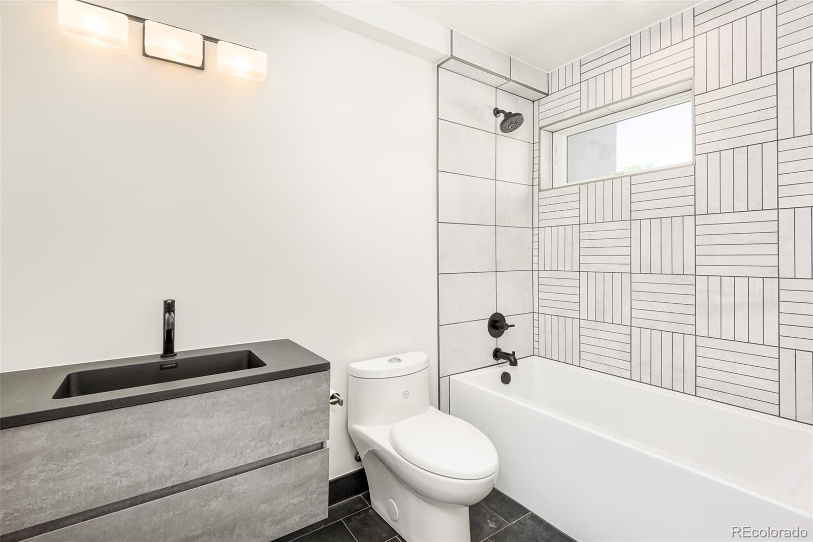 4461 Utica Street Denver, CO 80212 - Photo 25 of 40 a bathroom with a toilet a sink a mirror and shower