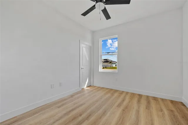 a view of empty room with window and ceiling fan