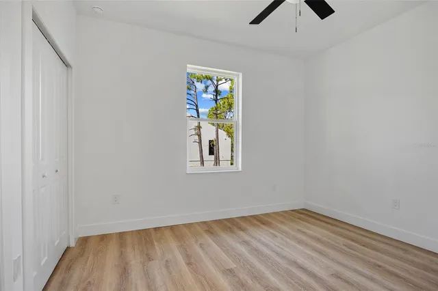 a view of empty room with wooden floor and fan