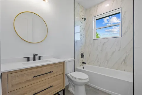a bathroom with a toilet a sink a mirror and bathtub