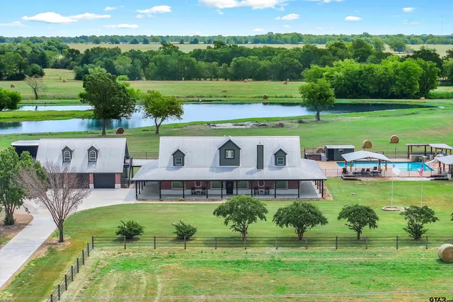 a view of a big house with a big yard and large trees