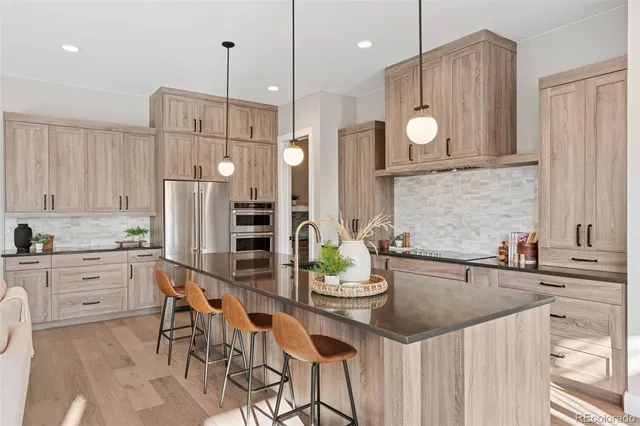 a kitchen with a sink a refrigerator and chairs