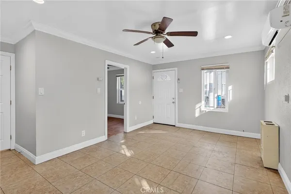 a view of an empty room with window and chandelier fan