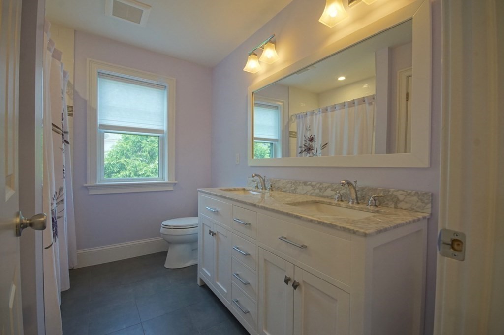 13 Warren Street Needham, MA 02492 - Photo 28 of 34 a bathroom with a granite countertop toilet a sink and a mirror
