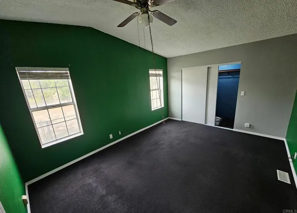 a view of an empty room with a window and a kitchen