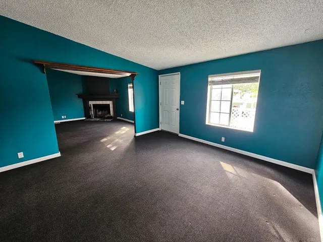 an empty room with fireplace and window