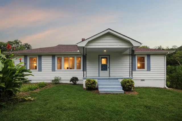 a kitchen with granite countertop a refrigerator a sink dishwasher a stove and white cabinets with wooden floor