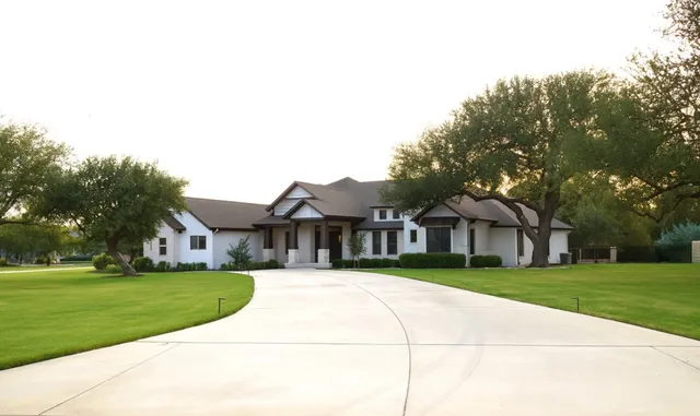 a view of a white house with a big yard and large trees