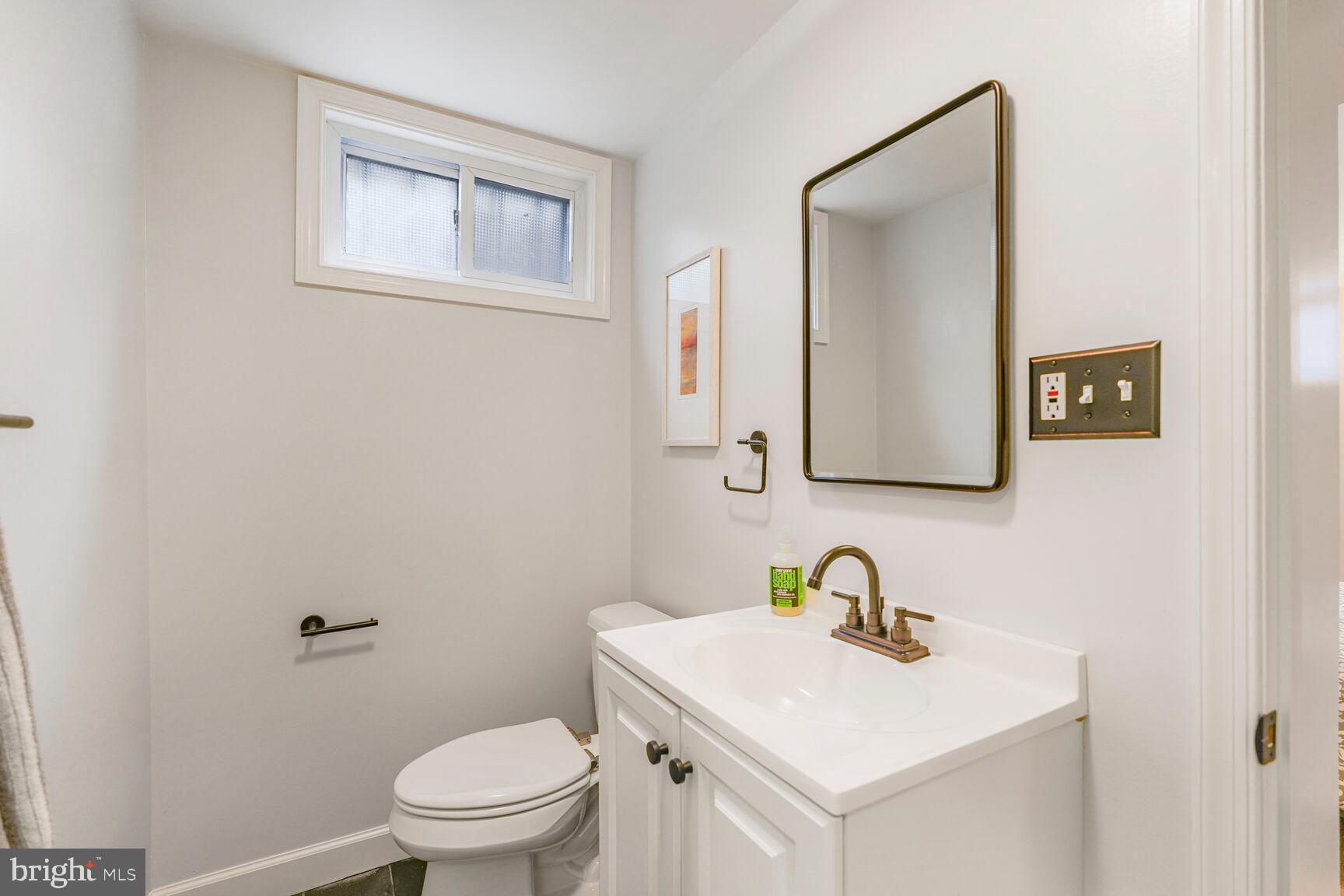 9213 Bradford Road Silver Spring, MD 20901 - Photo 28 of 34 a bathroom with a toilet a sink and mirror