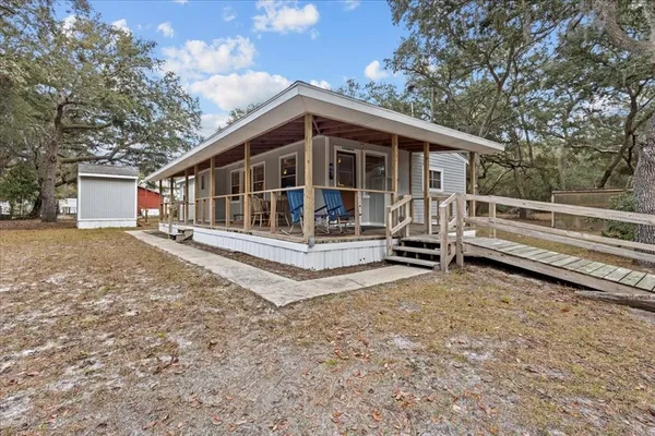 a view of house with backyard and trees in the background