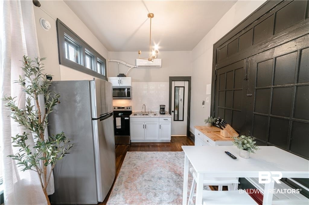 207 Michigan Avenue Mobile, AL 36604 - Photo 18 of 31 Kitchen with stainless steel appliances, dark wood-type flooring, light countertops, decorative light fixtures, and white cabinets
