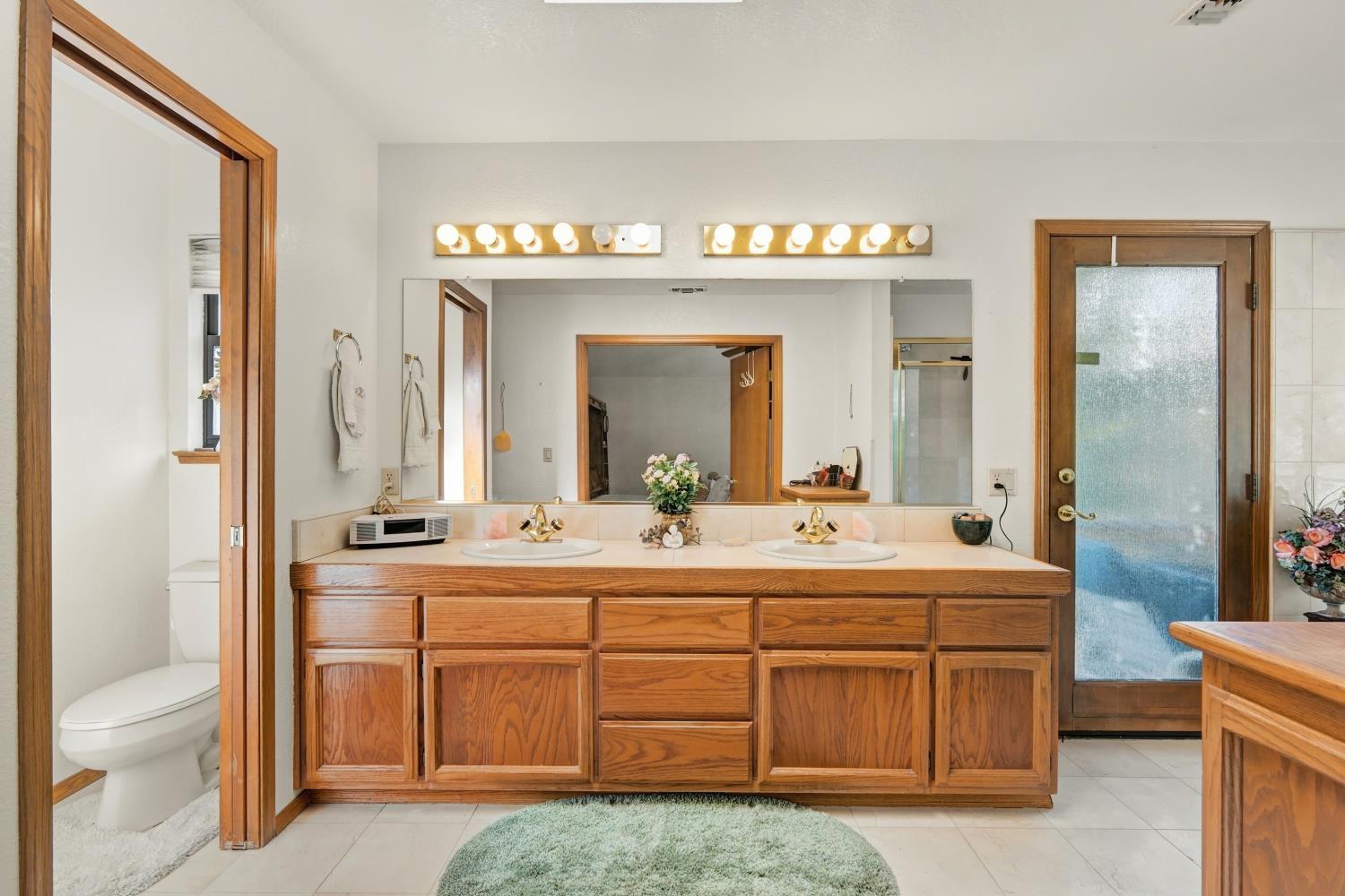 2952 Royce Drive Rescue, CA 95672 - Photo 31 of 70 Dual vanity with wood-finish cabinetry, integrated sinks, a large mirror, and overhead lighting