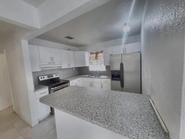 a kitchen with granite countertop a refrigerator and a sink