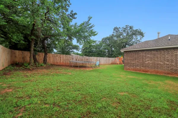 a view of a backyard with large trees and wooden fence