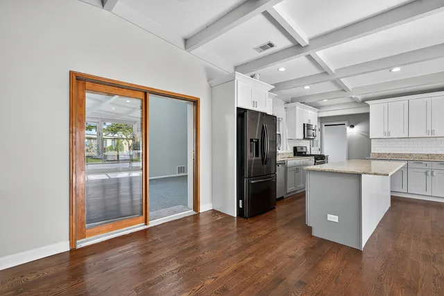 a kitchen with a refrigerator a sink and wooden floor