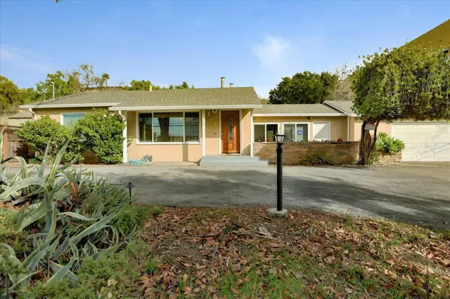 a front view of a house with a yard and potted plants