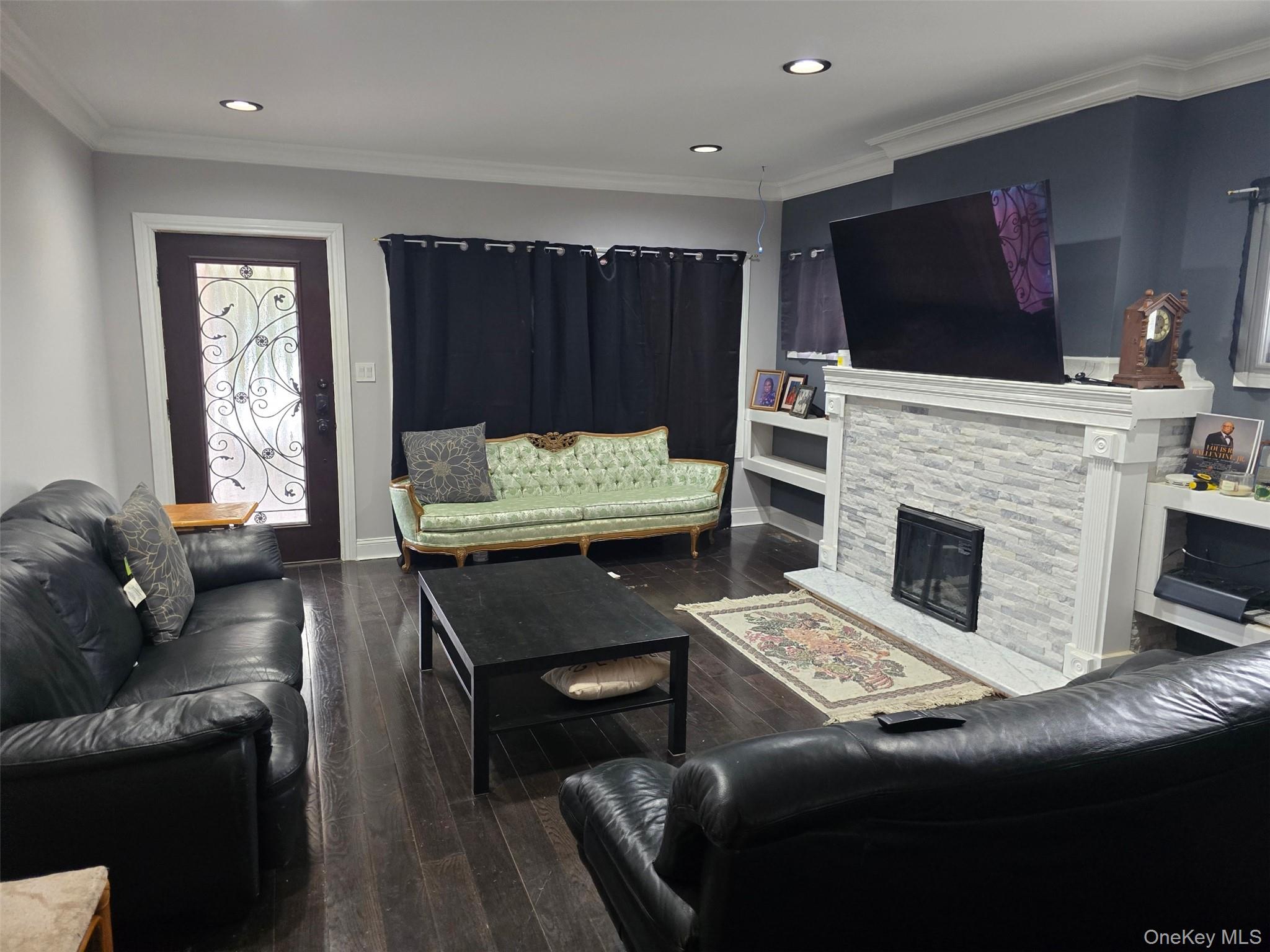 192-01 110th Road Queens, NY 11412 - Photo 4 of 11 Living room with crown molding, dark wood-type flooring, a fireplace, and recessed lighting