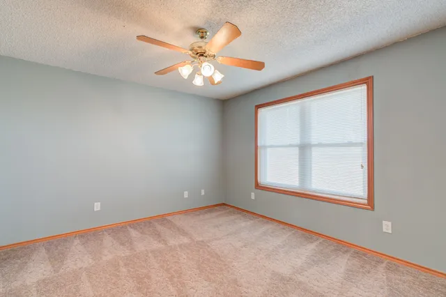 an empty room with windows and fan