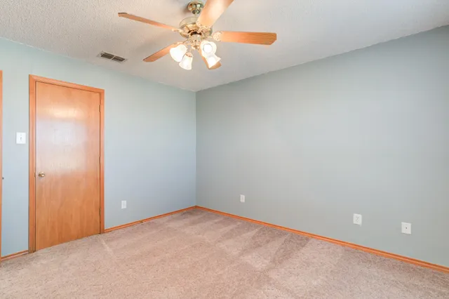 an empty room with a chandelier fan and windows