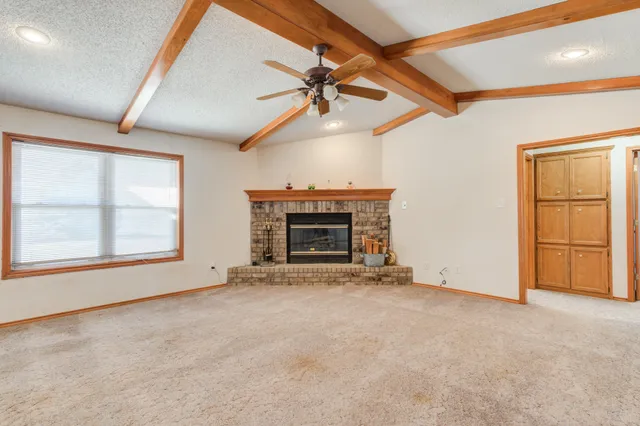 an empty room with windows fireplace and a ceiling fan