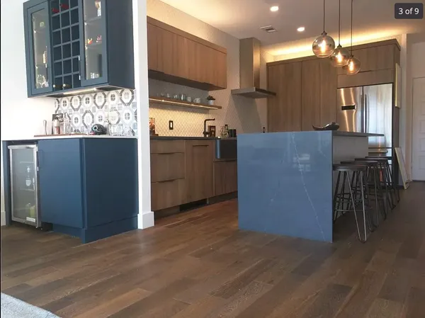 a kitchen with kitchen island granite countertop wooden floor a refrigerator and a sink