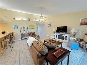a living room with furniture a flat screen tv and kitchen view