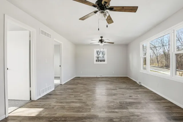 an empty room with a window and a ceiling fan