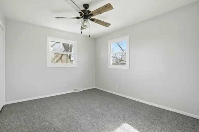 an empty room with a window and a fan