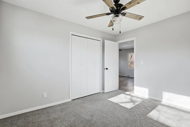 an empty room with a chandelier fan and windows
