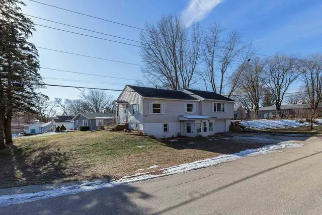 a front view of a house with a yard covered in snow