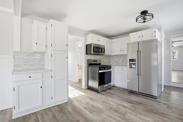 a kitchen with white cabinets and stainless steel appliances