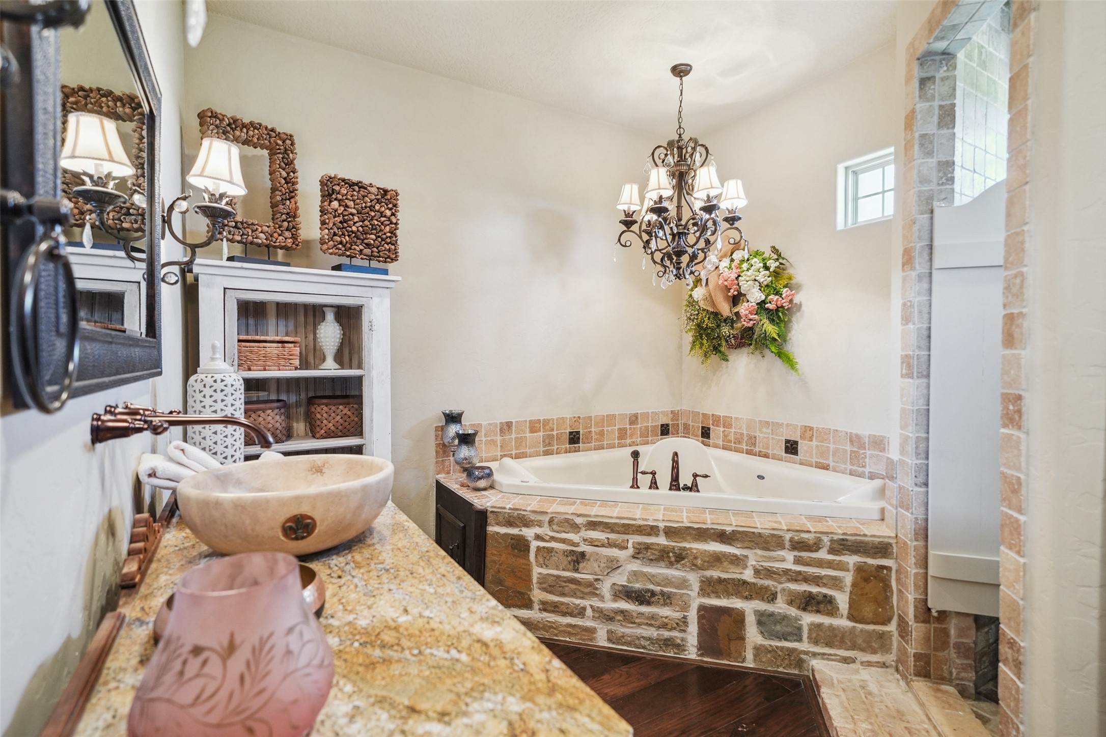 460 Bishop Road Huntsville, TX 77320 - Photo 23 of 50 The ensuite bathroom showcases a luxurious jacuzzi tub, a walk-in marble shower, and stunning Carrera marble walls and countertops, all illuminated by a magnificent chandelier, creating a spa-like retreat.
