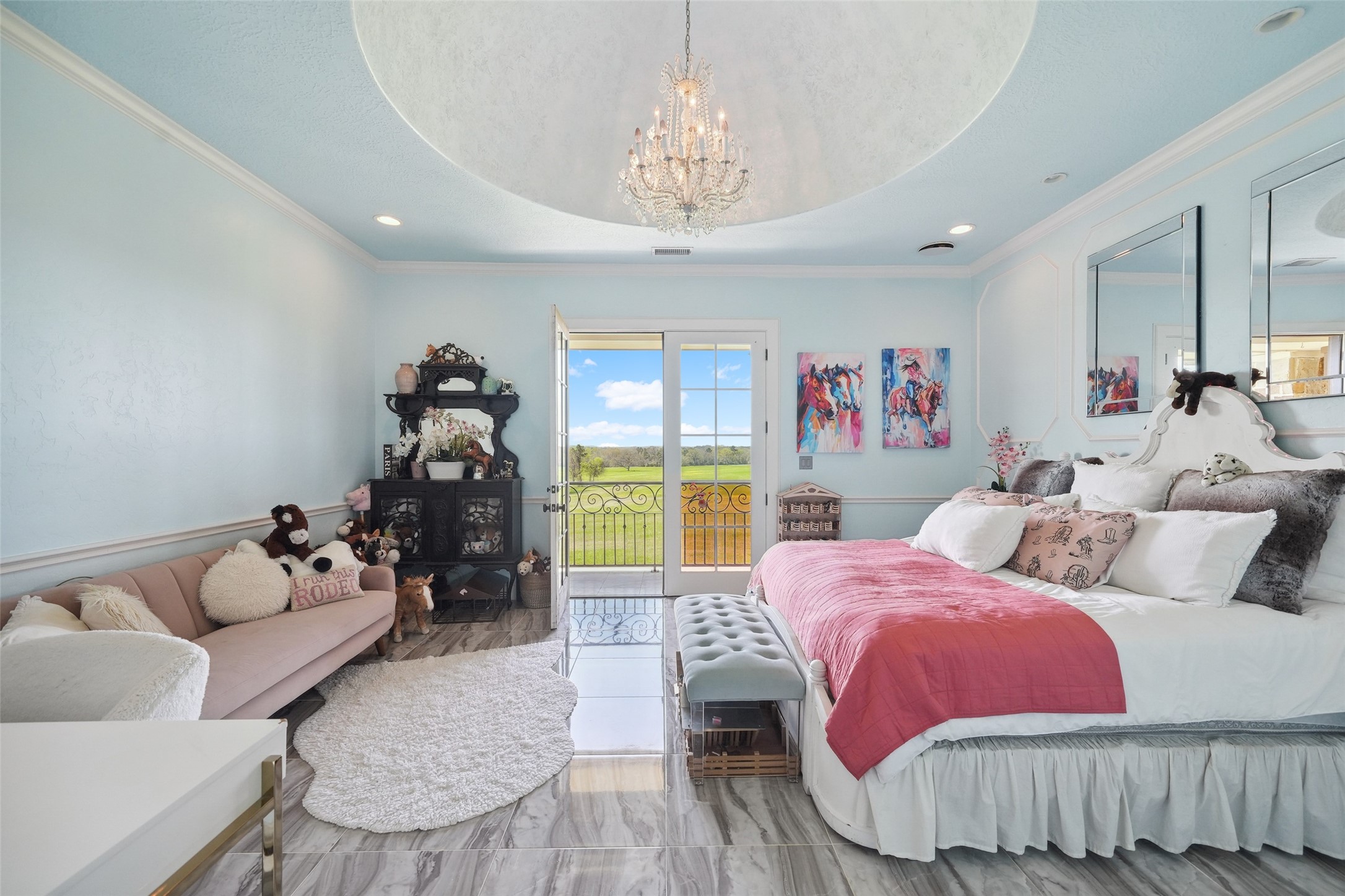 460 Bishop Road Huntsville, TX 77320 - Photo 24 of 50 This refined upstairs bedroom features a recessed ceiling with stained trim, complemented by a stunning crystal chandelier. Rich wood floors enhance the space, while a private balcony provides scenic views. Custom plantation shutters frame the windows, offering both privacy and natural light.